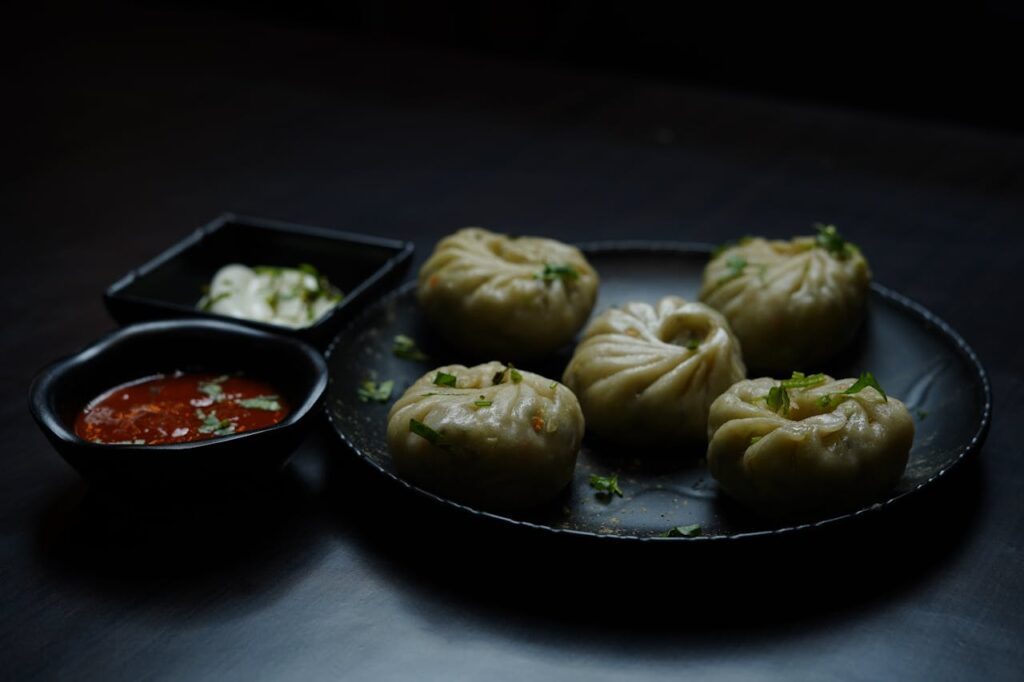 pexels-photo-18803174 A close-up of Tibetan momos served with spicy and creamy sauces.