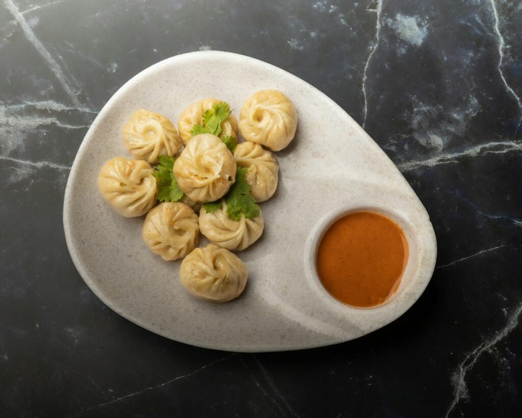 pexels-photo-28445593 A plate of traditional Nepalese momos with spicy chutney. Perfect for food enthusiasts seeking authentic flavors.