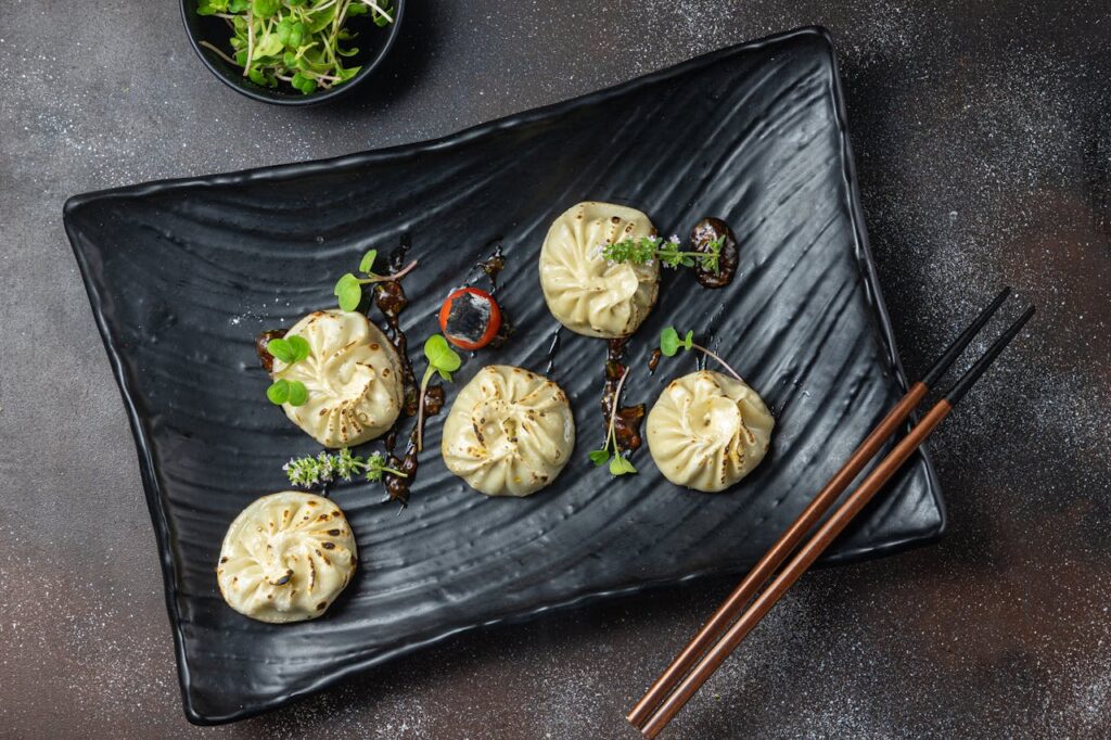 pexels-photo-5409010 Delicious steamed dumplings garnished with fresh microgreens on a black plate, perfect for food photography.